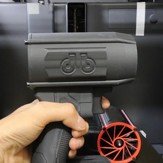 Hand holding a black futuristic toy gun with textured grip and bold logo, gaming accessory